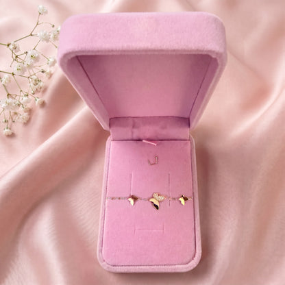 Bracelet papillons dans un écrin en velours rose ouvert, posé sur un satin rose